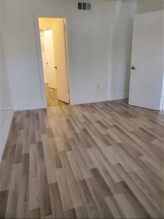 a view of a room with wooden floor and white door