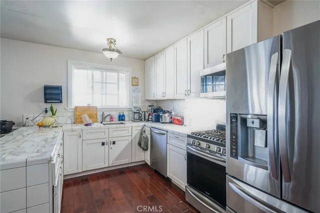 a kitchen with granite countertop a refrigerator stove and sink