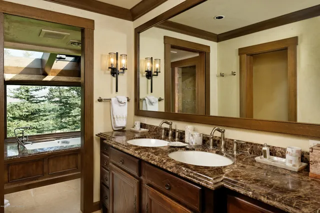 a bathroom with a granite countertop sink a mirror and shower