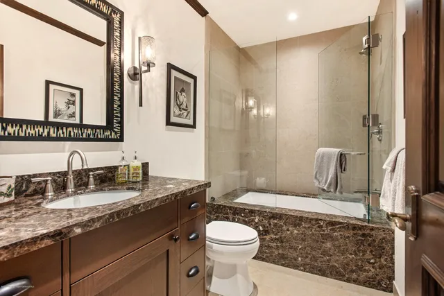 a bathroom with a granite countertop toilet sink and mirror