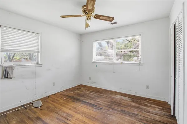 a view of empty room with wooden floor and fan