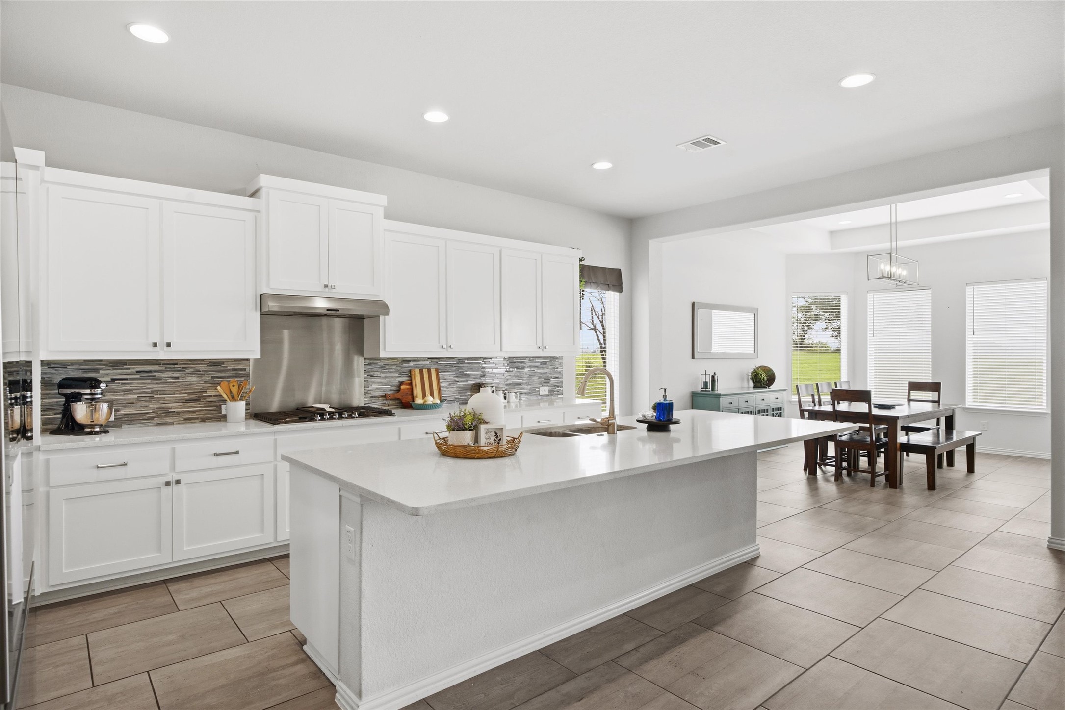 192 Raptor Beak Way Cedar Creek, TX 78612 - Photo 1 of 38 Kitchen featuring a large central island with a light stone countertop, white cabinetry, a tile backsplash, stainless steel appliances, and recessed lighting