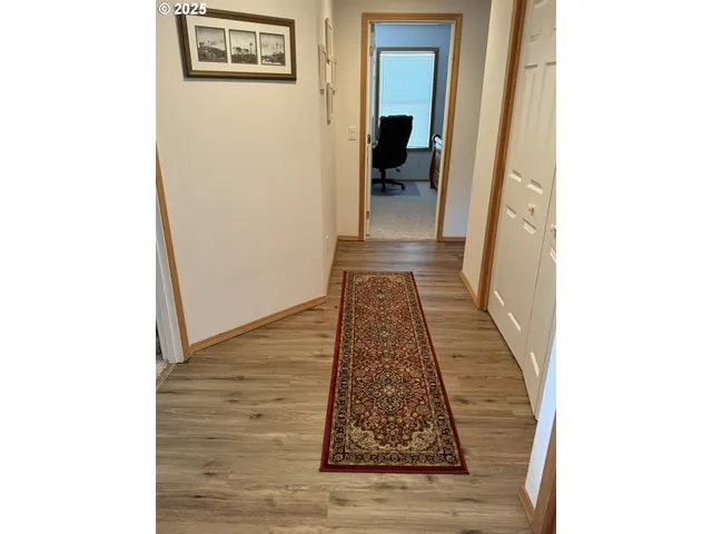 a view of a hallway with wooden floor and a bathroom