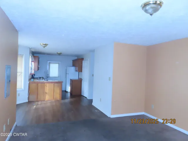 a view of an empty room and a kitchen