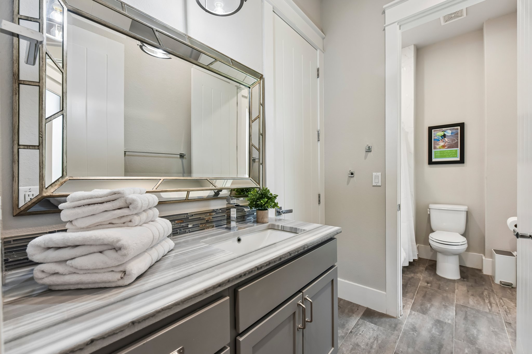 2203 Improver Road Spicewood, TX 78669 - Photo 16 of 38 A well-lit bathroom boasts a sleek vanity with a large, decorative mirror and durable tile flooring.