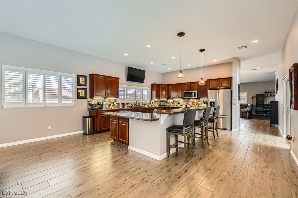 647 Foxhall Road Henderson, NV 89002 - Photo 17 of 82 Kitchen with light wood-style flooring, stainless steel appliances, backsplash, and a kitchen island