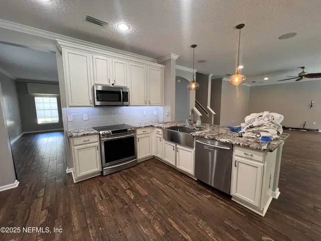 a kitchen with stainless steel appliances granite countertop a sink stove and wooden floor