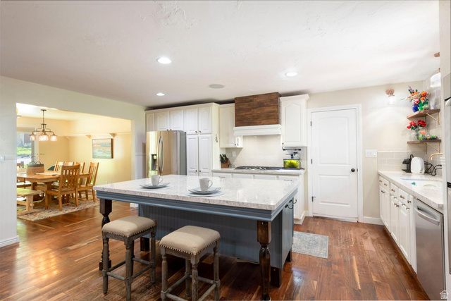 9676 Mt Jordan Road Sandy, UT 84092 - Photo 17 of 38 Kitchen featuring a central island with a light-colored countertop, white cabinetry, wood-finish flooring, recessed lighting, and a wood-paneled range hood