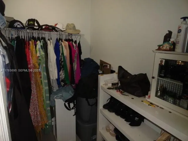 a view of walk in closet with clothes and shoes
