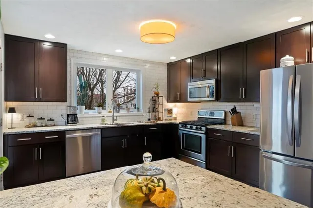 a kitchen with stainless steel appliances kitchen island granite countertop a sink stove and refrigerator
