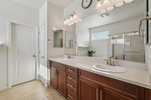 a bathroom with a double vanity sink a mirror and a shower