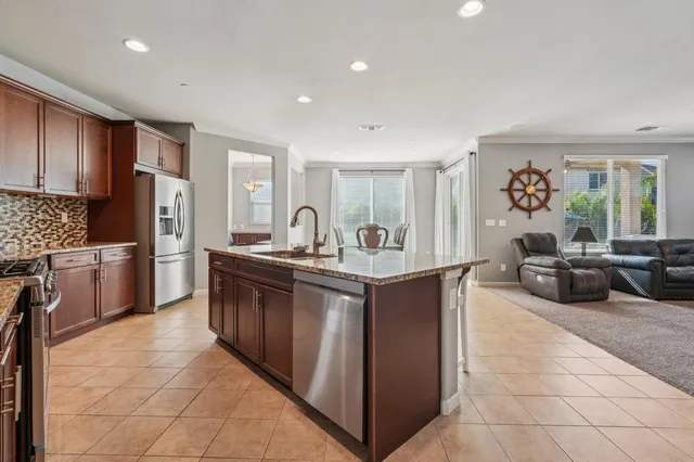 a spacious kitchen with stainless steel appliances granite countertop a sink and a refrigerator
