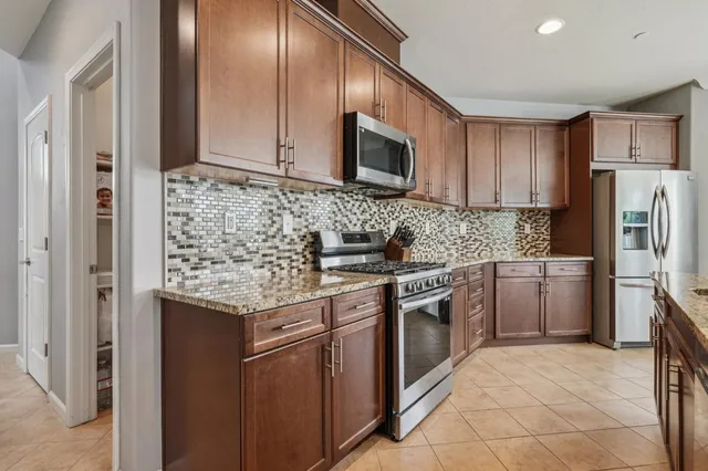 a kitchen with stainless steel appliances granite countertop a stove top oven a refrigerator and a sink