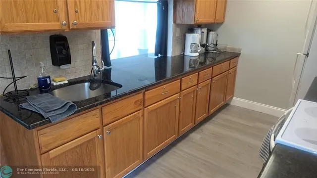 a kitchen with granite countertop a sink dishwasher stove and cabinets