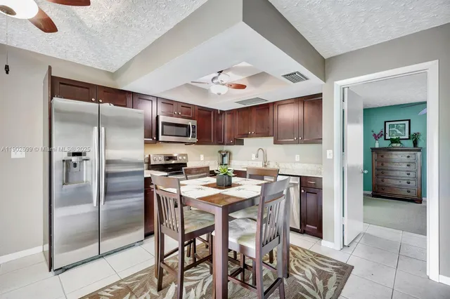 a kitchen with granite countertop a refrigerator oven a sink a stove and chairs