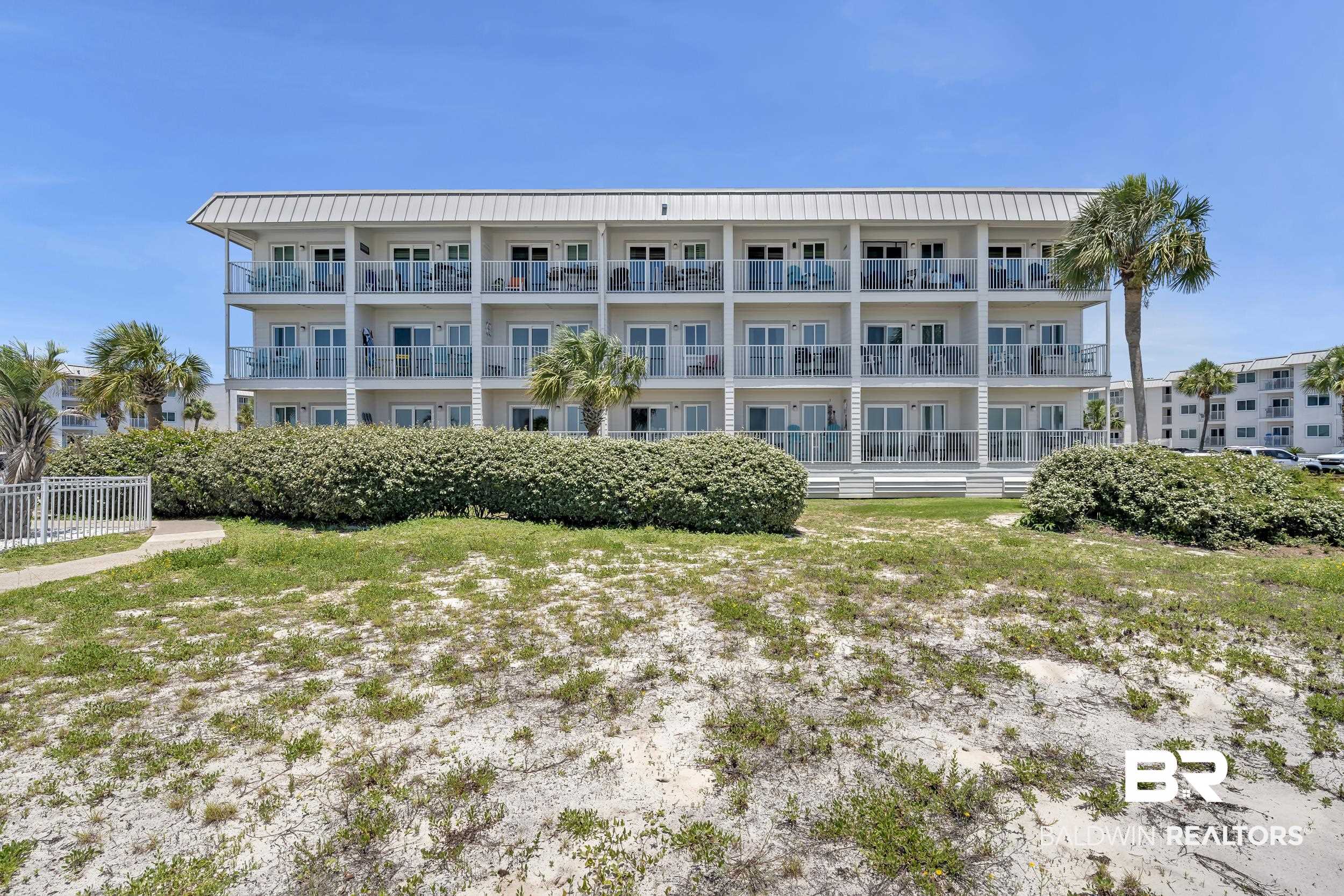 400 Plantation Road, Unit 2118 Gulf Shores, AL 36542 - Photo 40 of 59 Multi-story building featuring a white facade, multiple balconies with glass railings, a metal roof, and surrounding palm trees