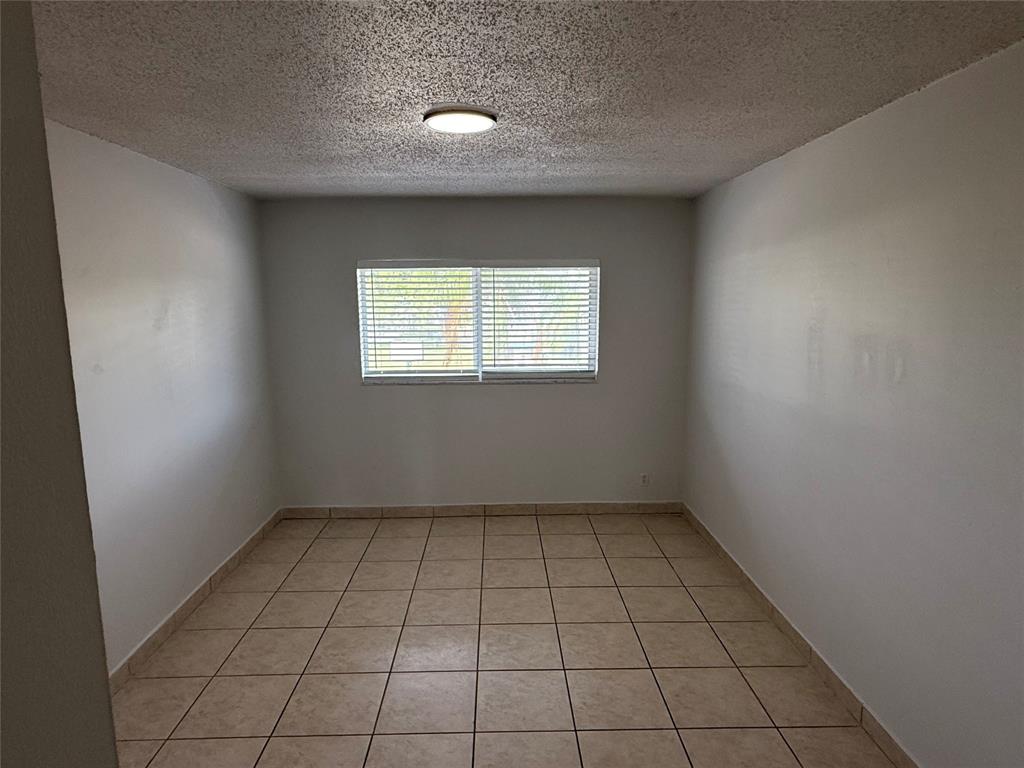 720 Northeast 7th Street, Unit 7 Hallandale Beach, FL 33009 - Photo 6 of 7 an empty room with white walls and tiles