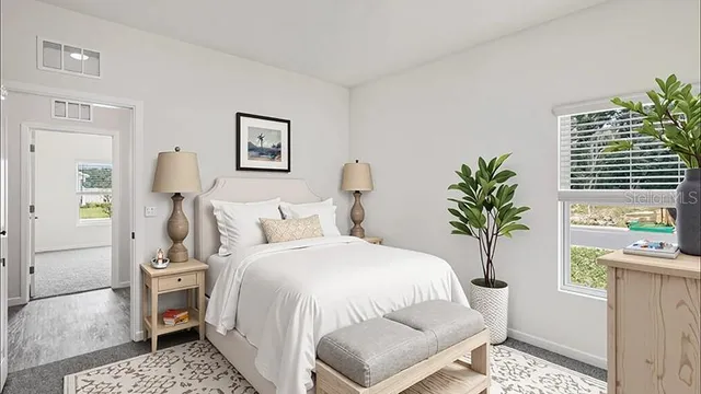 a bedroom with a bed and a potted plant on the dresser