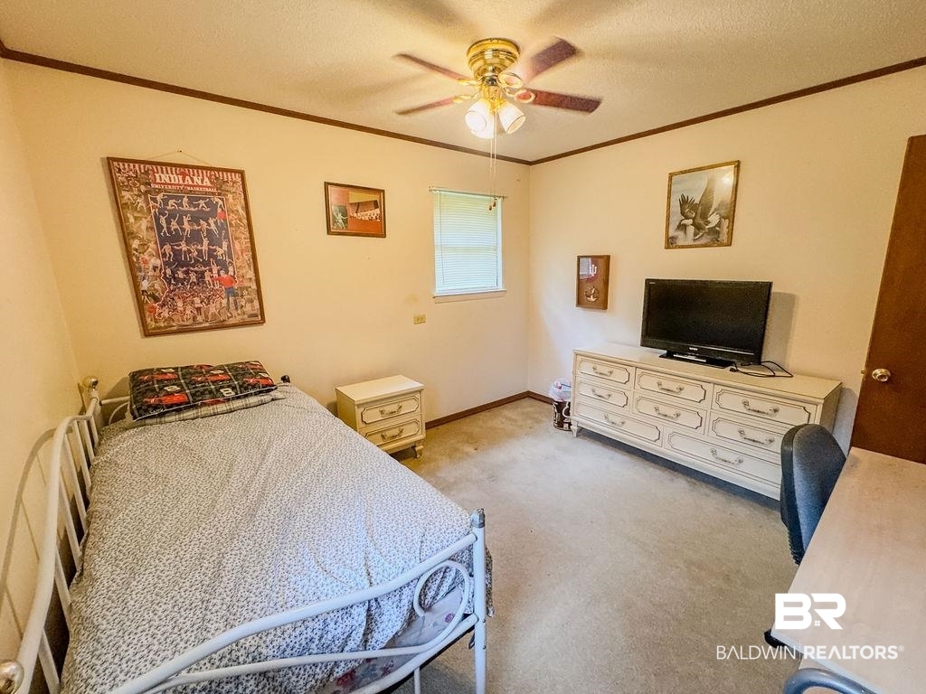 1456 Allen Walker Road Grove Hill, AL 36451 - Photo 23 of 28 Carpeted bedroom with crown molding, a textured ceiling, and ceiling fan