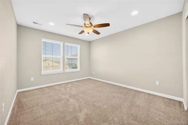 an empty room with ceiling fan and window