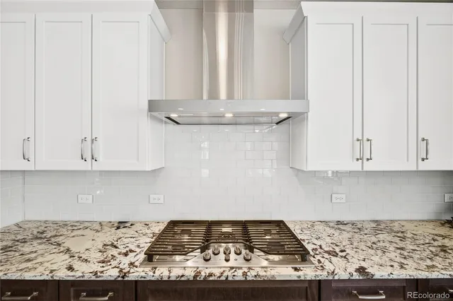 a kitchen with granite countertop white cabinets and a stove