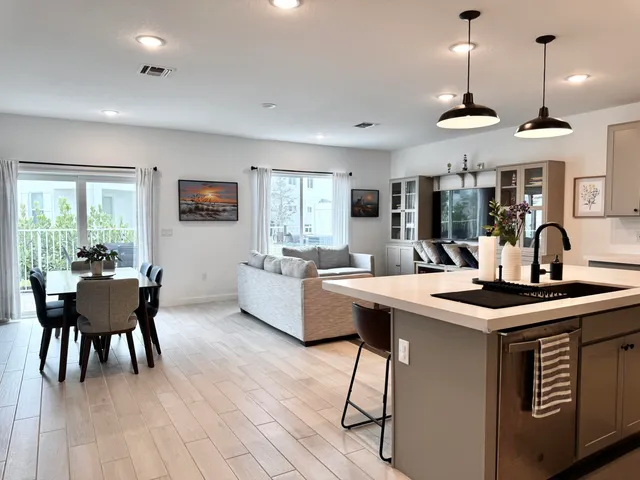 a kitchen with stainless steel appliances granite countertop a stove a sink dishwasher a dining table and chairs with wooden floor