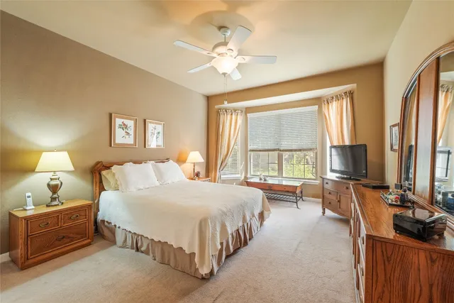 a spacious bedroom with a bed and a flat tv screen