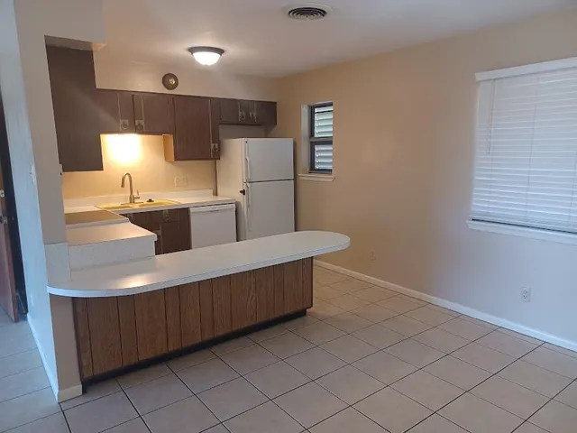 a kitchen with kitchen island sink and refrigerator