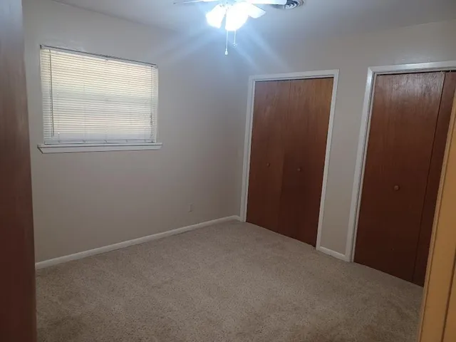 an empty room with a window and a fan