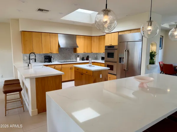 a kitchen with sink a refrigerator and chairs