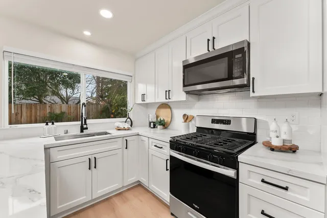a kitchen with stainless steel appliances white cabinets and a stove top oven