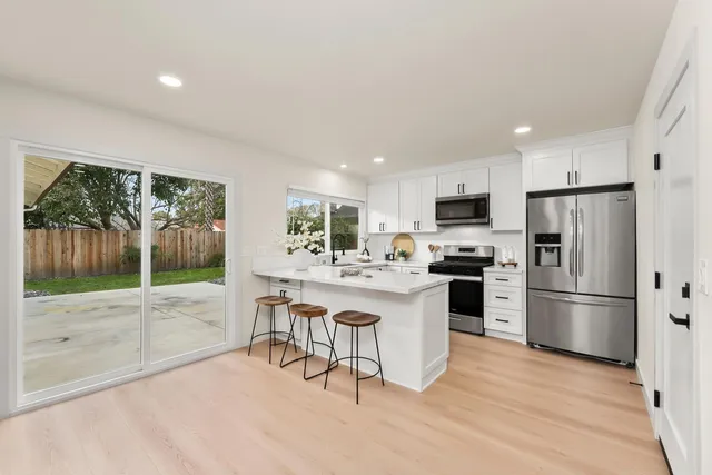 a kitchen with a refrigerator a sink dishwasher a stove and a refrigerator with wooden floor