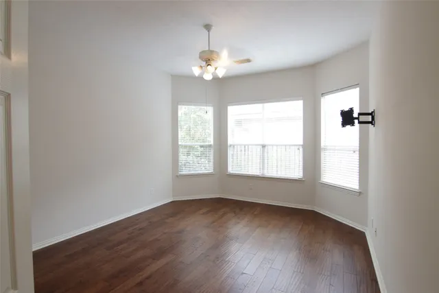an empty room with wooden floor chandelier and windows