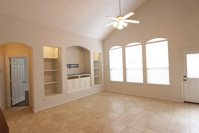 a view of an empty room with a window and kitchen view