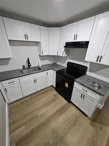 a kitchen with granite countertop a stove sink and cabinets