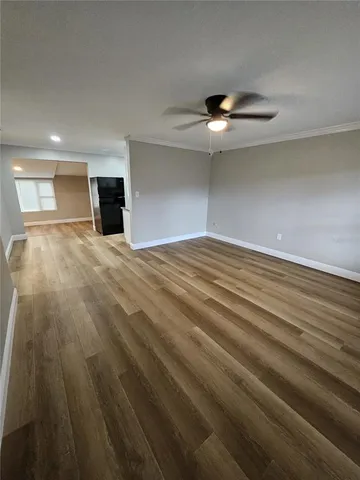 an empty room with wooden floor ceiling fan and windows