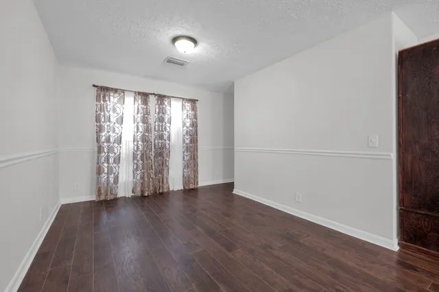 a view of an empty room with wooden floor fireplace and a window