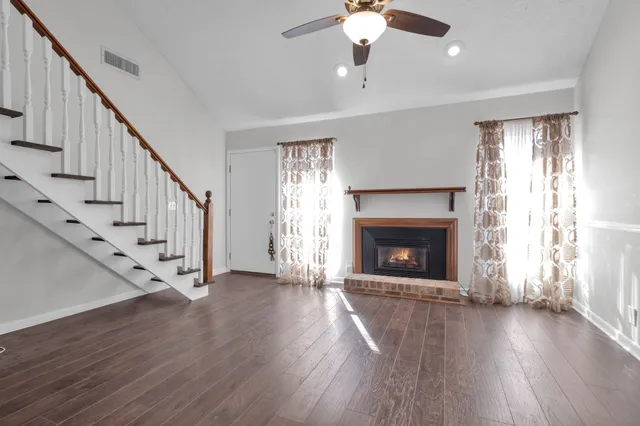 an empty room with wooden floor fireplace and windows