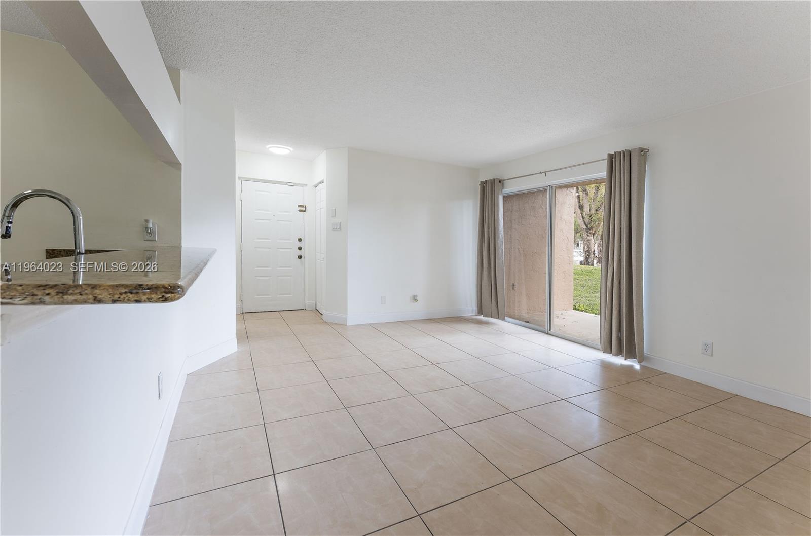10521 Southwest 157th Place, Unit 102 Miami, FL 33196 - Photo 3 of 15 a view of a kitchen with a sink and an empty room