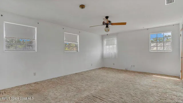 an empty room with windows and fan
