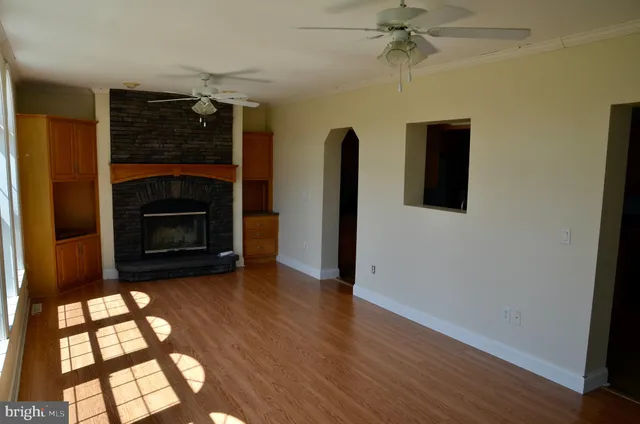 an empty room with wooden floor closet and windows