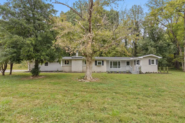 a house that is sitting in the grass with large trees