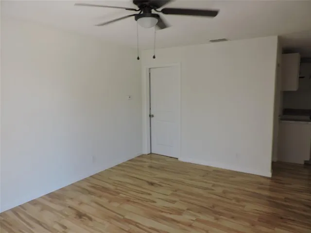 a view of a room with wooden floor and a ceiling fan