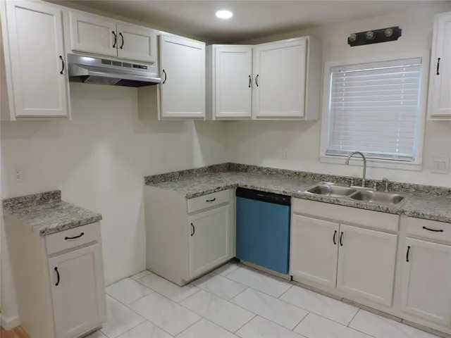 a kitchen with granite countertop a sink and dishwasher a stove with wooden cabinets