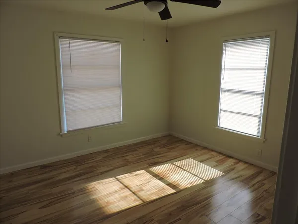 a view of empty room with wooden floor and fan