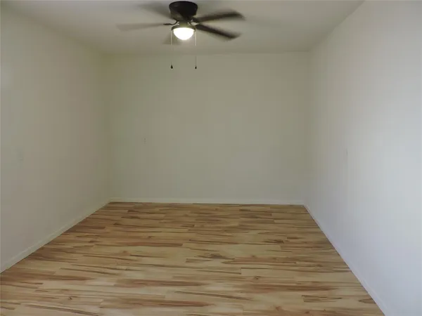 an empty room with wooden floor and fan