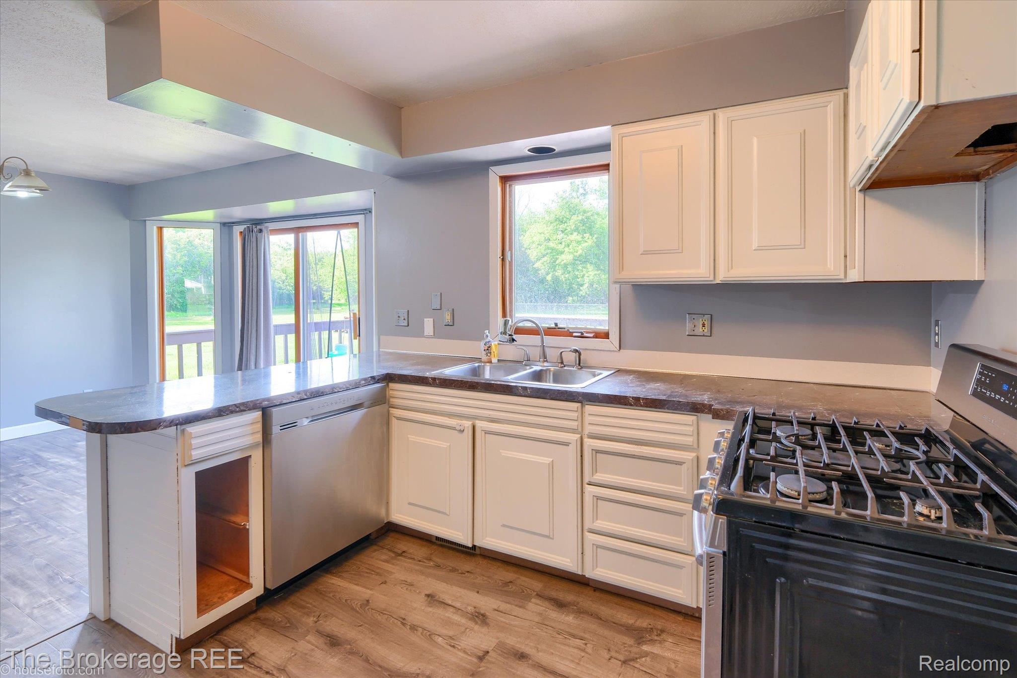 5495 East Coldwater Road Flint, MI 48506 - Photo 21 of 44 Kitchen featuring wood-finish flooring, white cabinetry, a gas range, a stainless steel dishwasher, and a double basin sink