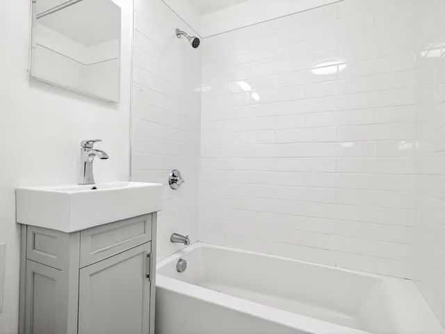 a bathroom with a bathtub sink vanity and a shower