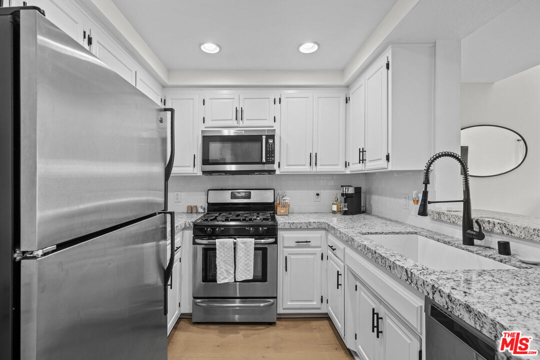 8601 Falmouth Avenue, Unit 404 Playa del Rey, CA 90293 - Photo 8 of 28 a kitchen with stainless steel appliances granite countertop a sink and a stove
