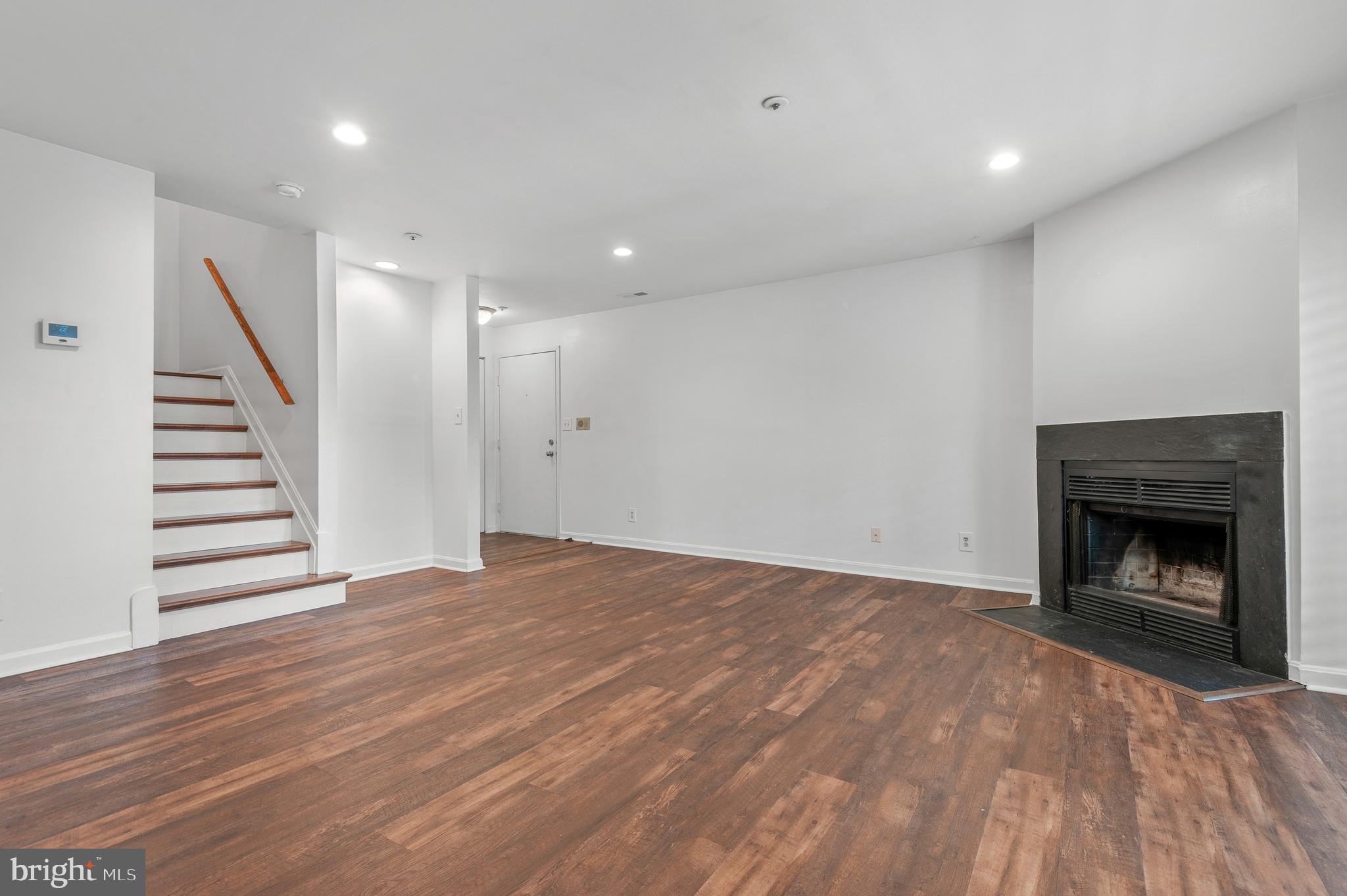 4942 Columbia Road, Unit 5 37 Columbia, MD 21044 - Photo 5 of 36 a view of an empty room with wooden floor fireplace and staircase